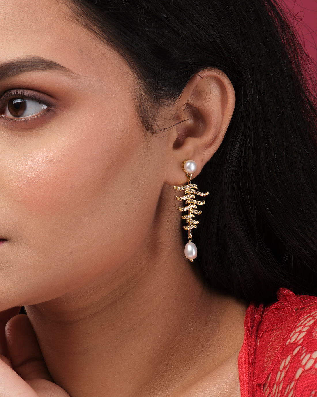 Vintage Hang Earrings by Chandrani Pearls India feature a gold zigzag design with pearl accents, showcased on a white cube for a touch of elegance against a softly blurred floral background.