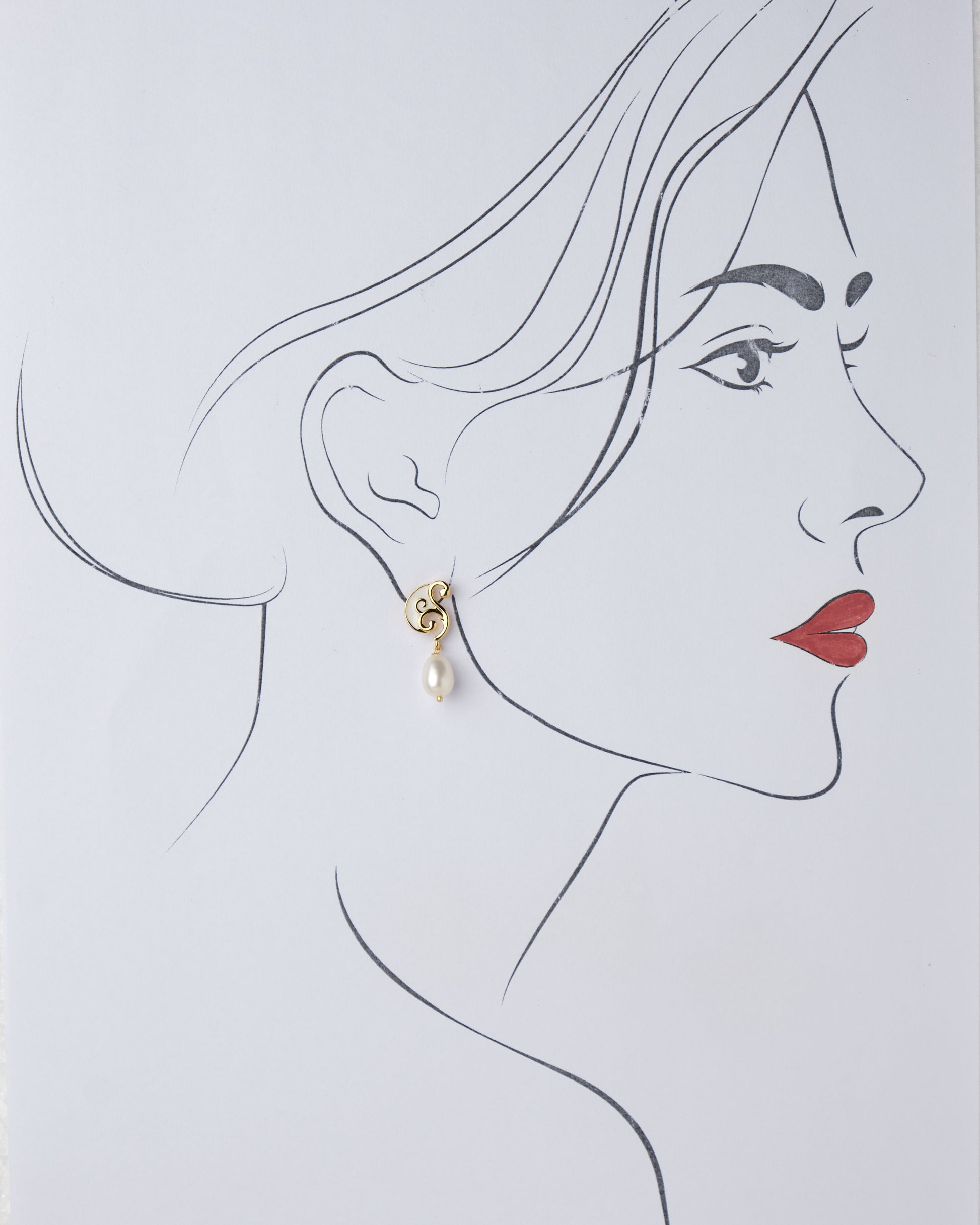 A drawing of a woman's face with a pair of Chandrani Pearls Sophisticated Dainty Pearl Drop Earrings.