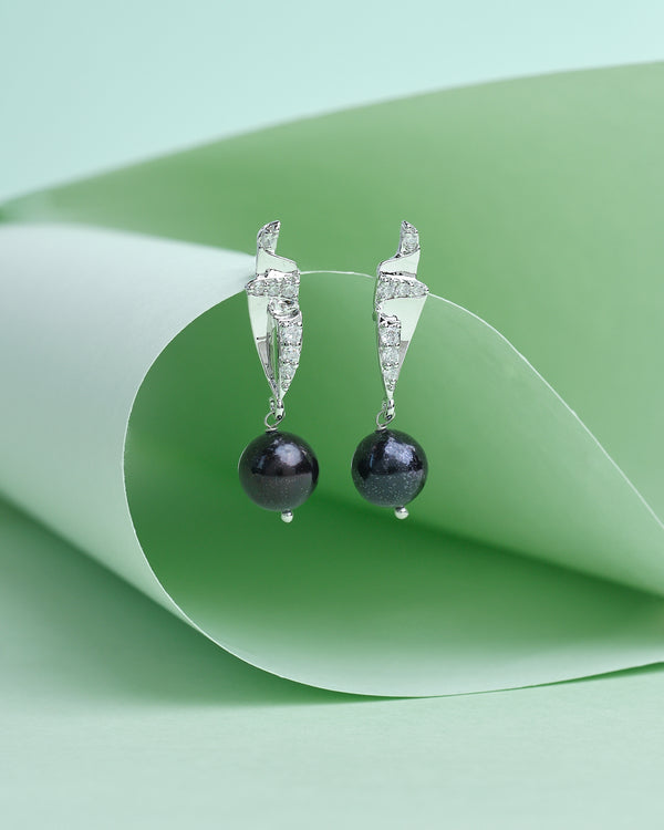 Refined style for any look by Chandrani Pearls features silver drop earrings with black spherical beads, set against a light green curved paper backdrop, adding effortless beauty and glow to your ensemble.
