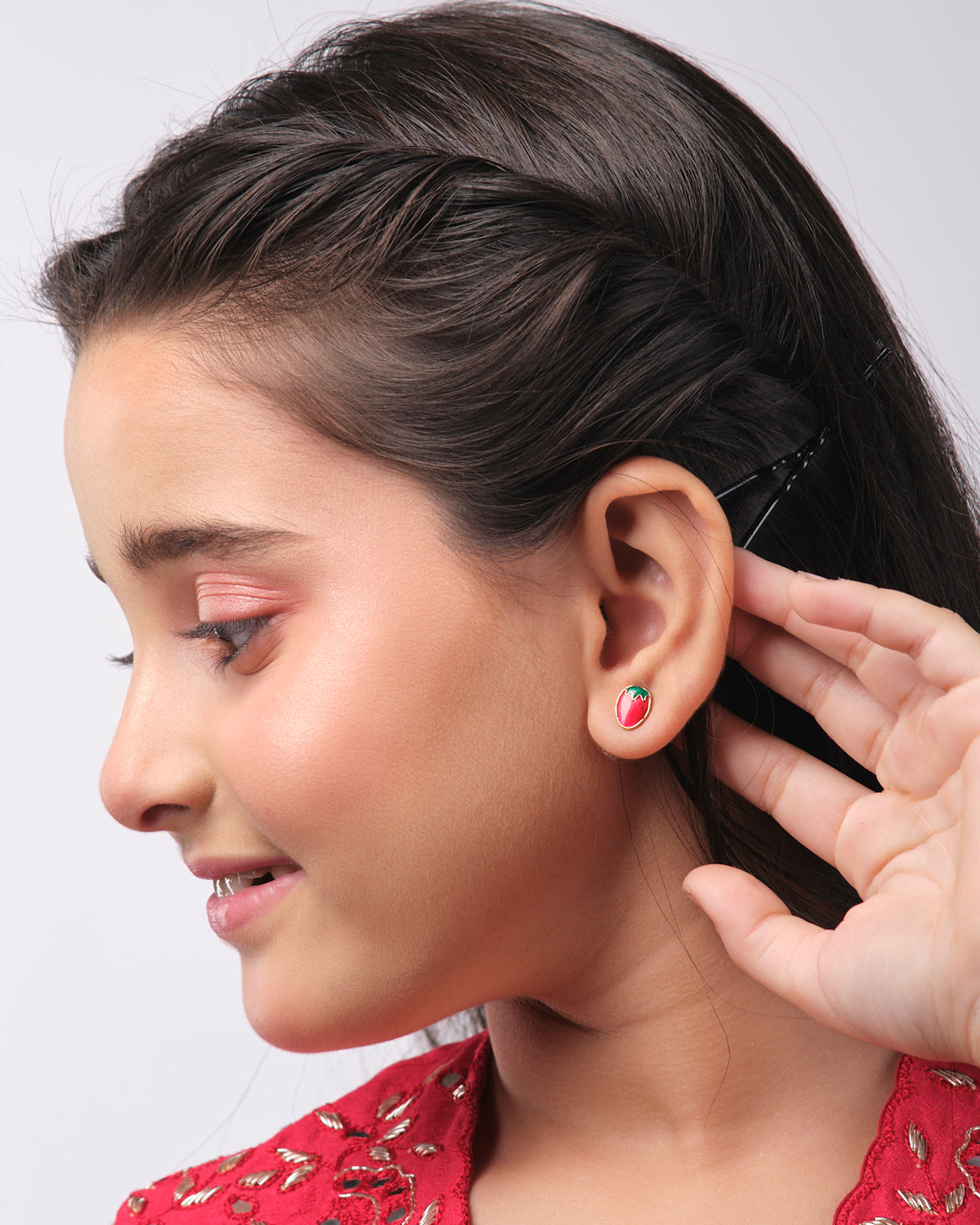 The Stawberry Stud Earring by Chandrani Pearls India features red strawberry-shaped earrings on a star-shaped background with a silhouette of a cat holding an umbrella.