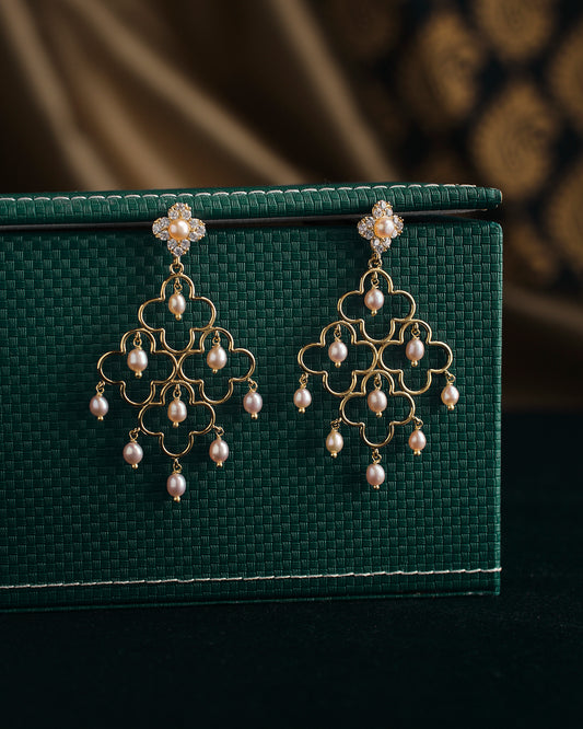 Gulabi Dhara Pearl Earrings by Chandrani Pearls showcased on a textured green surface.