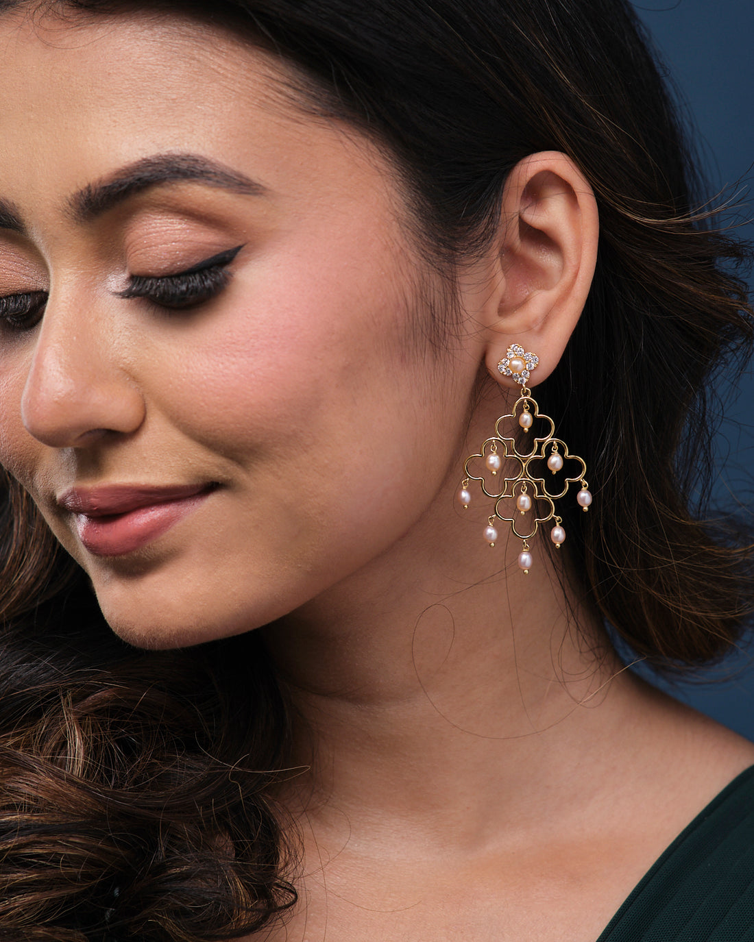 Gulabi Dhara Pearl Earrings by Chandrani Pearls showcased on a textured green surface.