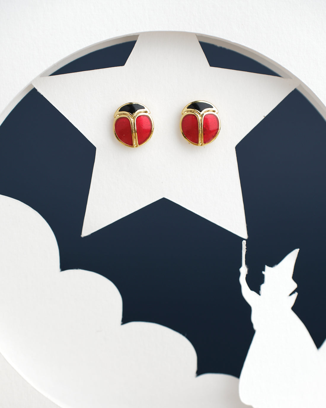 Chandrani Pearls India's Cute Stud Earrings feature a red and black round design on a white star-shaped cutout, complete with a casting figure silhouette at the bottom.