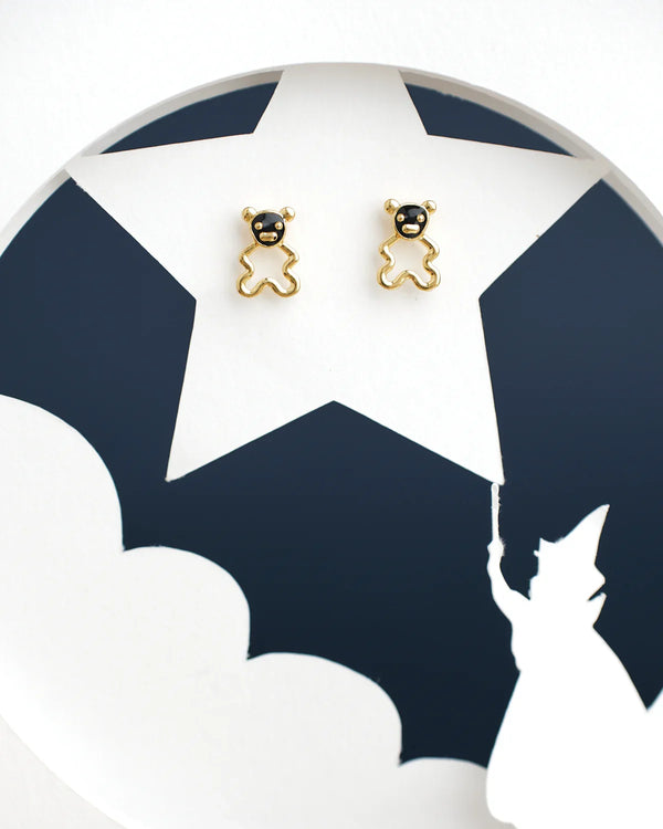 The Pretty Teddy Stud Earrings by Chandrani Pearls India are on a white surface with a black star pattern and silhouette of a girl holding an umbrella.