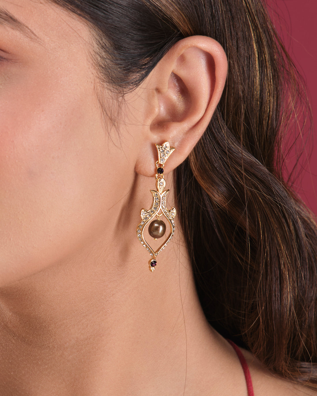 Elevate your style with Trendy Hang Earrings by Chandrani Pearls India—ornate gold dangle earrings adorned with elegant central pearls and small gemstones, beautifully presented on a white cube.
