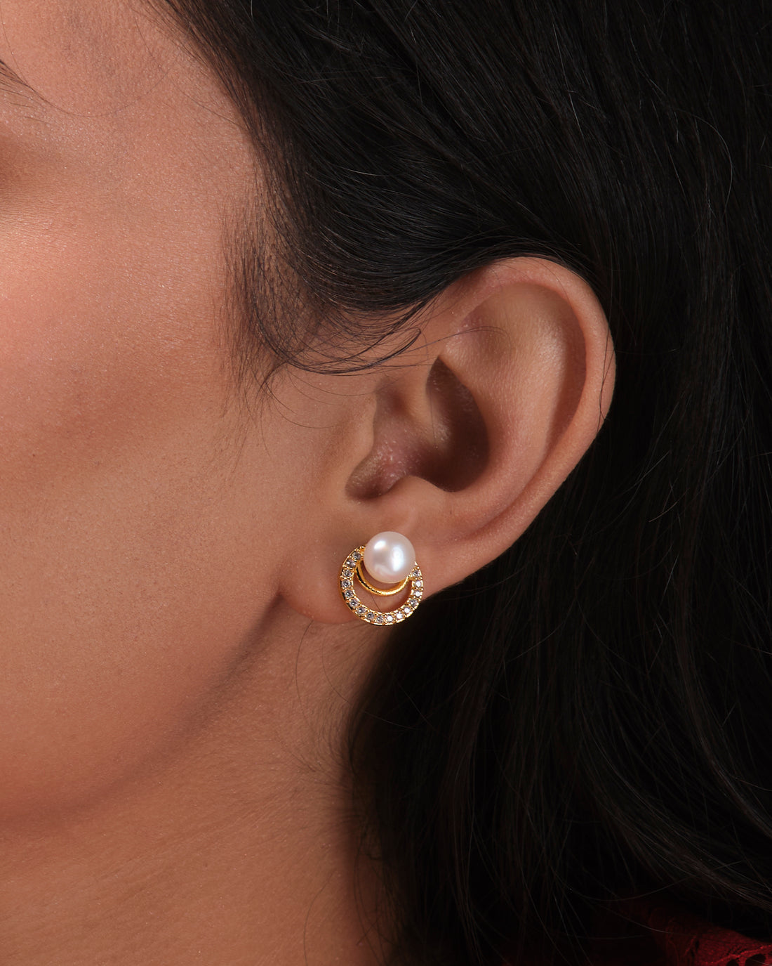 The Cute Stud Earrings by Chandrani Pearls India feature round pearls and small clear stones, offering classic elegance and style. They are displayed on a white block with a blurred background.