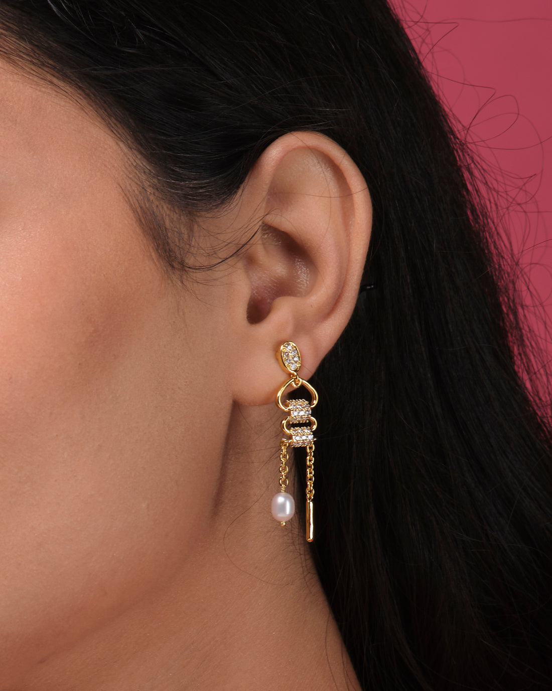 The Fashionable CZ Hang Earrings by Chandrani Pearls India feature lustrous clear stones, delicate chains, and a single dangling pearl, elegantly displayed on a white cube.