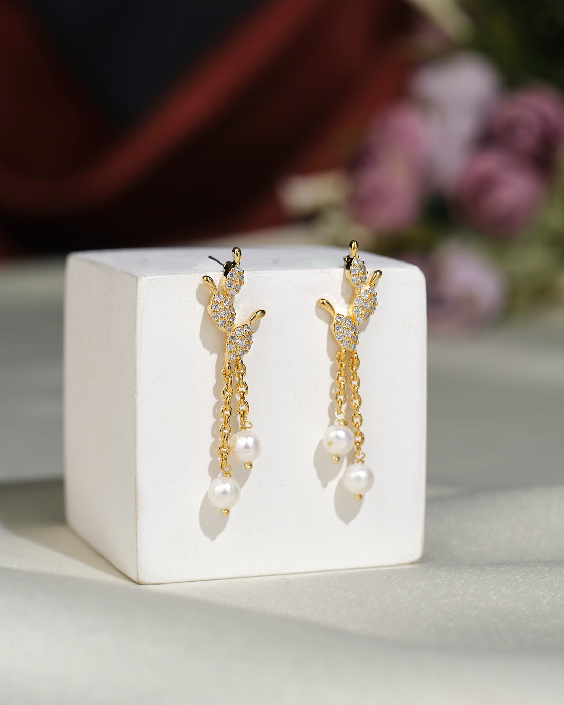 Cute Hang Earrings by Chandrani Pearls India feature butterfly tops, sparkling crystals, and dangling pearls for a sophisticated touch. Presented stylishly on a white block, they’re perfect to elevate any outfit.