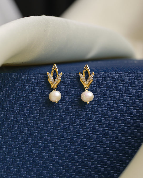 Understated yet dazzling, these Chandrani Pearls studs feature luminous white pearls and sparkling CZ stones in a geometric design, elegantly showcased on a dark blue background for a sophisticated look.