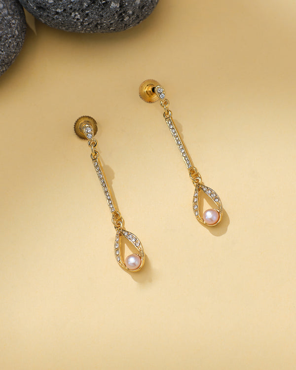 Chandrani Pearls' Pearl Hoops with CZ Embellishments feature a pink pearl teardrop set with sparkling stones, elegantly displayed on a beige background beside dark stones.