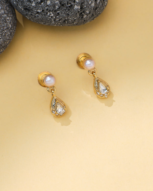 Chandrani Pearls’ Drop CZ Pearl Earrings feature glowing pearl studs and teardrop-shaped CZ gemstones, displayed on a light yellow surface with textured stones—an elegant touch for your formal wear.