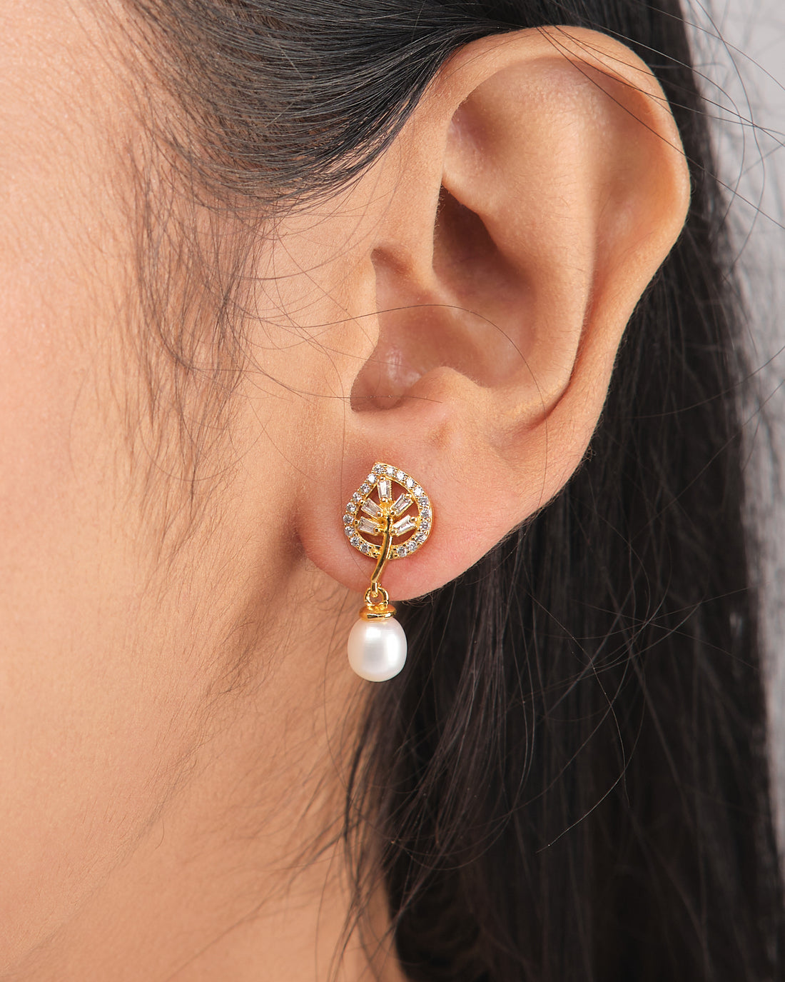 Sparkling Duo Silver Earrings by Chandrani Pearls feature a leaf-shaped design with clear stones and dangling pearls, radiating moonlight charm—an exquisite choice for lovers of delicate jewelry. Displayed on a white cube with a purple ribbon nearby.
