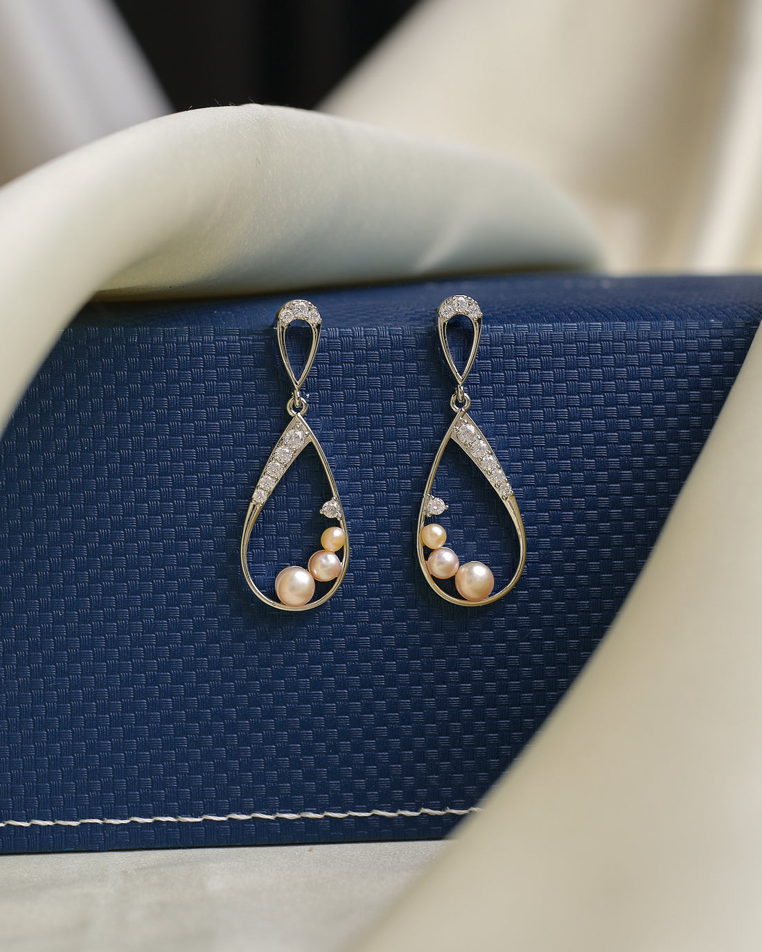 Chandrani Pearls' Sophisticated pearl drops, accented by dazzling CZ crystals, are showcased on a textured blue box with cream fabric—ideal for adding evening elegance to any outfit.