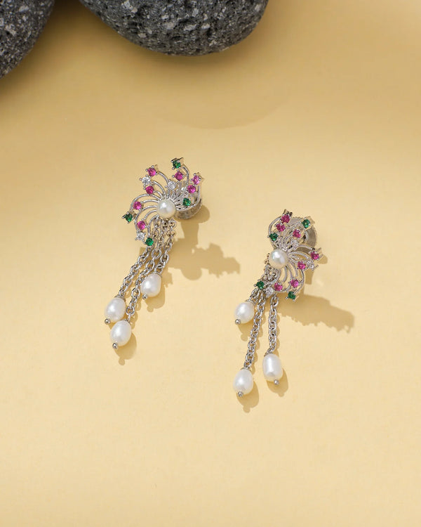 Chandrani Pearls Dangling Pearl Earrings feature pink and green stones, CZ chain links, and pearl drops, elegantly displayed on a light beige surface.