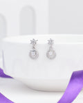 Chandrani Pearls' Floral Inspired Demifine Silver CZ Earrings, featuring star-shaped studs and gem-encrusted drops, are displayed on a white bowl with a purple ribbon—stylish festive jewelry perfect for any occasion.