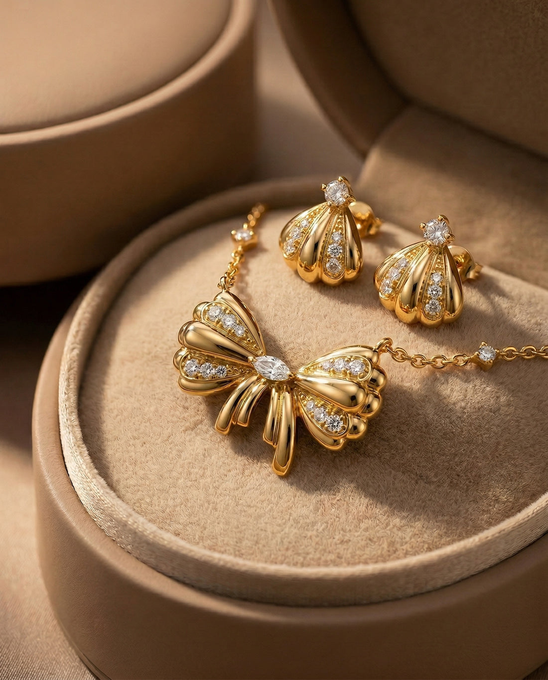 Gold bow necklace with matching earrings on a white background