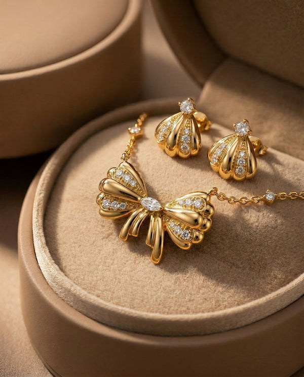 Gold butterfly necklace and earrings on a beige jewelry box