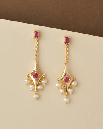 Ethnic Pearl Hanging Jhumkas with pink gemstones and pearl accents on a beige background by Chandrani Pearls India.